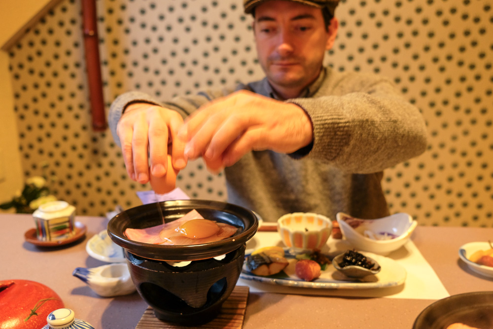 man breaks eggs on grill in Japan