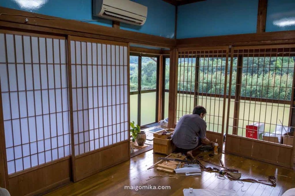 man in japanese style house fixing shoji screen doors with and without paper