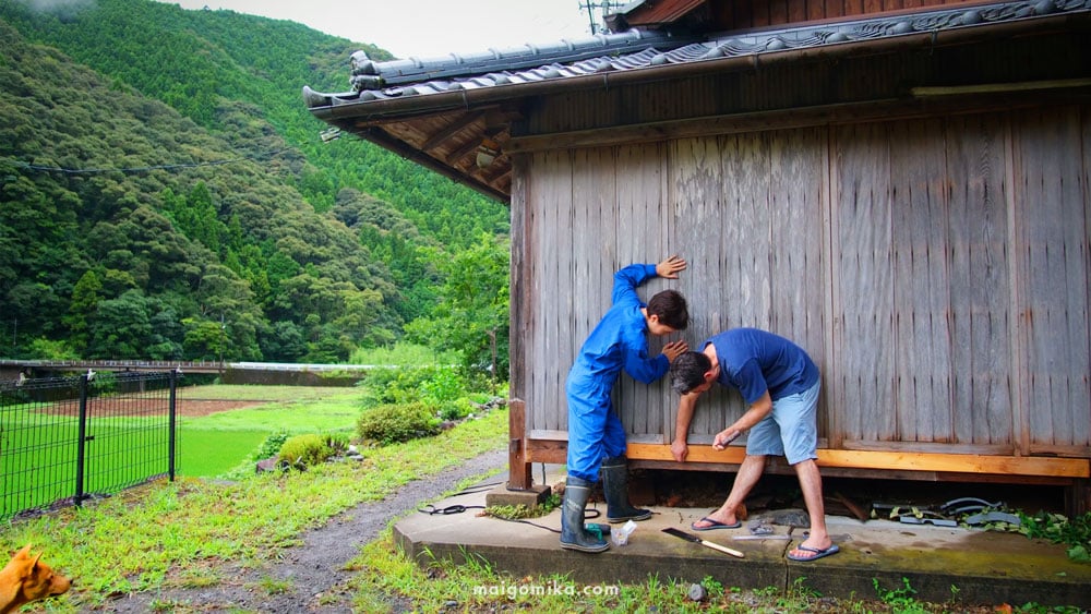 two people wearing blue setting up storm doors on traditional Japanese house